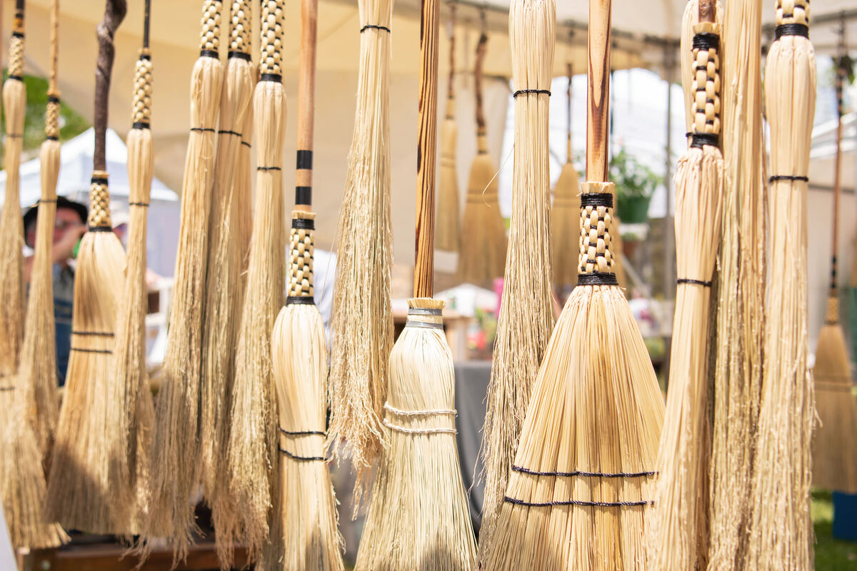 Handmade straw brooms hanging at a booth