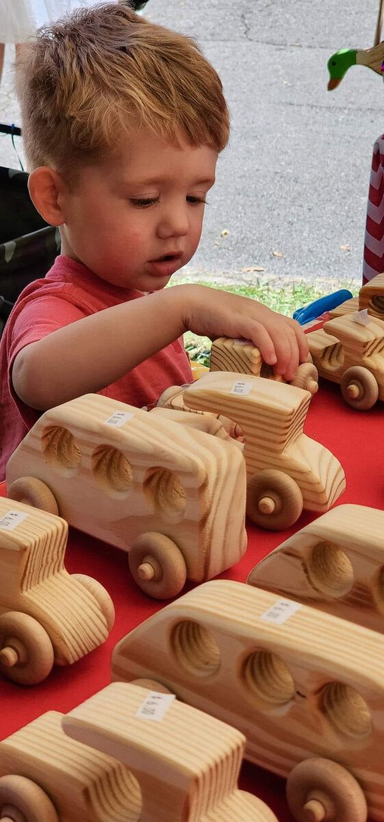 A little boy playing with handmade wooden toy cars
